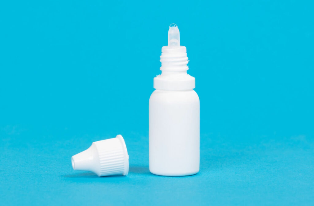 An opened bottle of eye drops against a blue background.