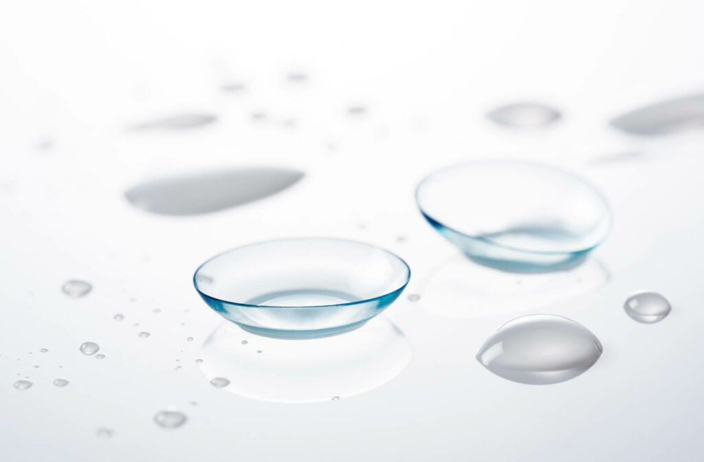 two contact lenses are on a glass surface with drops of saline.