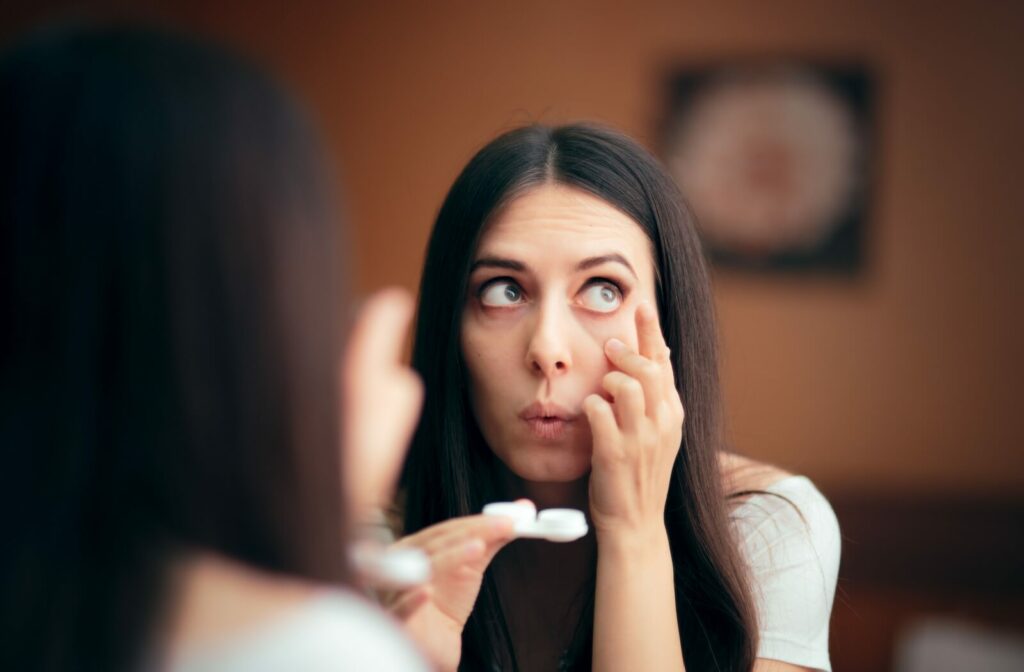 A person moving their eyes while looking in the mirror and holding a contact lens case is trying to locate their missing lens.