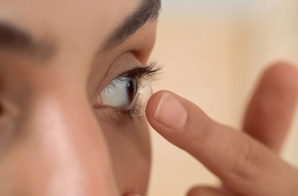 A close up of a person putting a contact lens into their eye using their finger