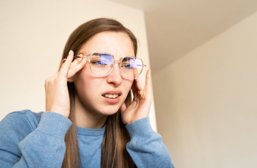 A person pulling their eyes to squint in order to see better through their glasses