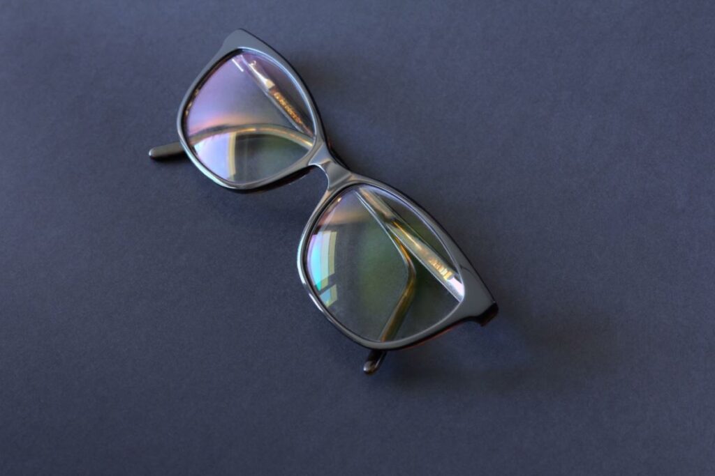 A pair of glasses on a black table with reflective lenses