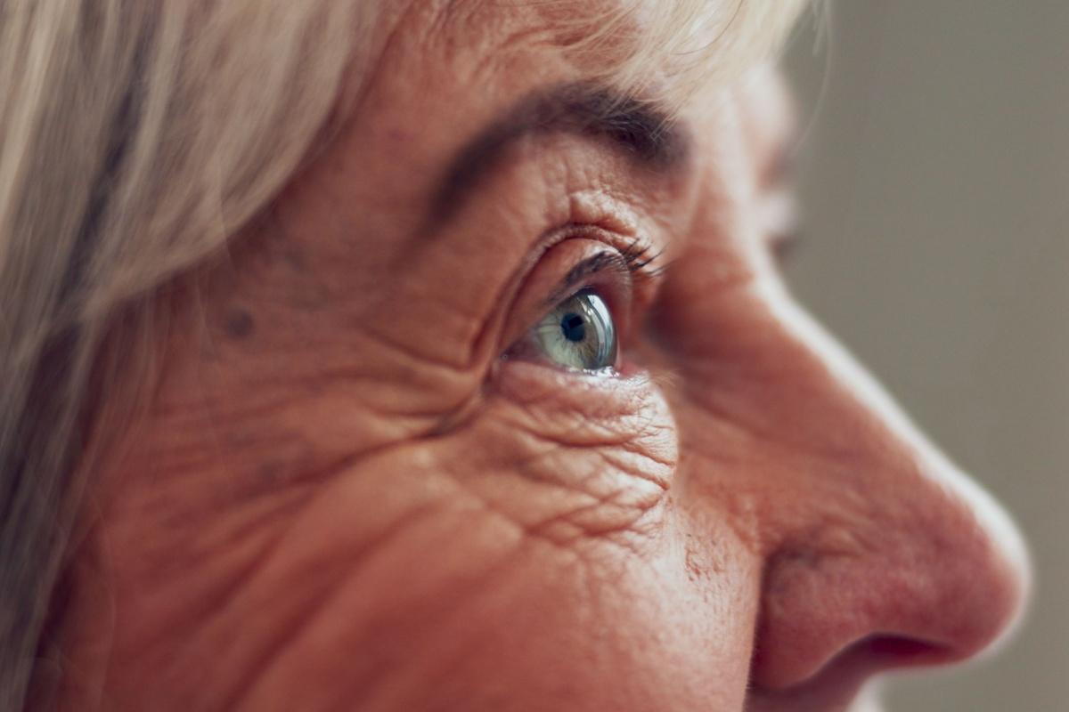 a close up view from the side of a senior person face showing their blue eye