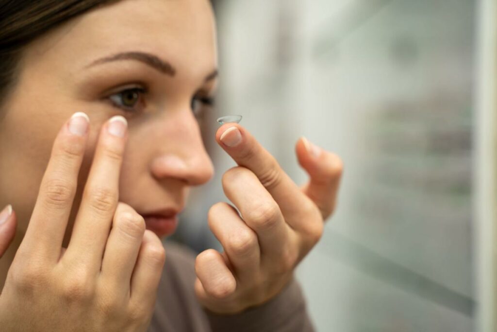 A person putting a contact lens into their eye