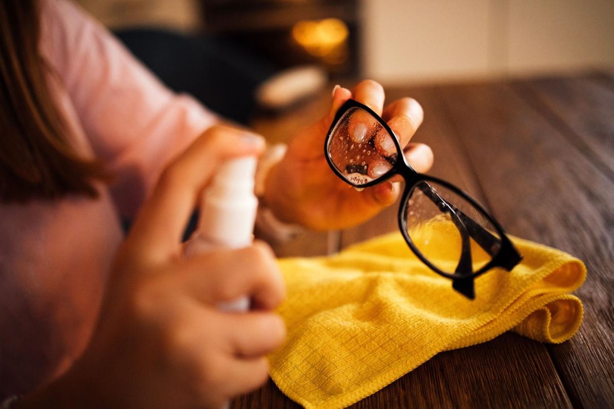 Glasses being sprayed with specialized cleaner and a cloth